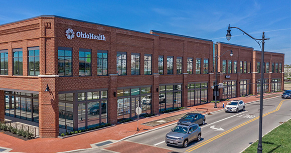 brick building with sidewalk and cars driving