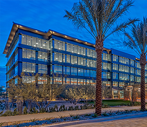 Multi-story building lined with large windows, surrounded by palm trees.